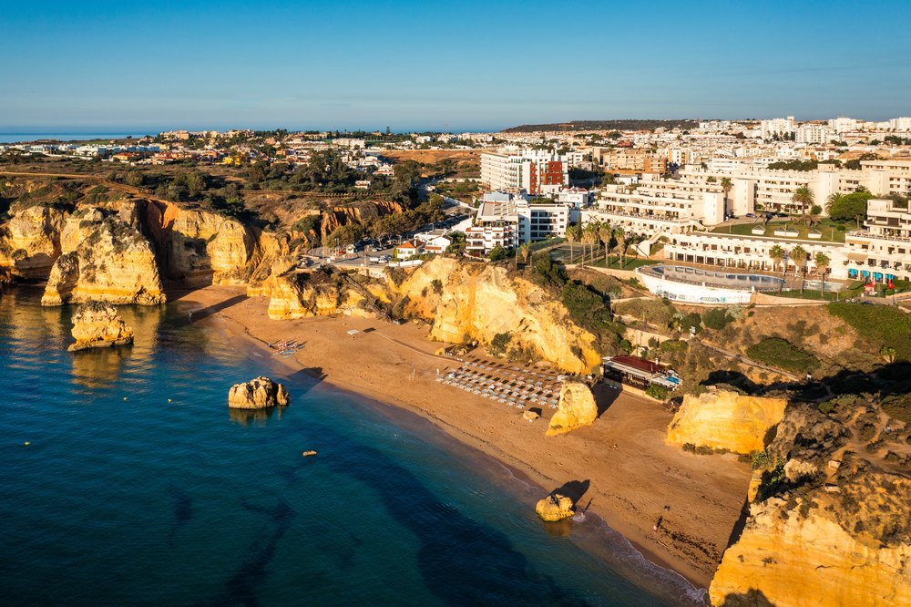 Plaża Dona Ana w Lagos między złotymi skałami, nad nią hotele i domy miasta