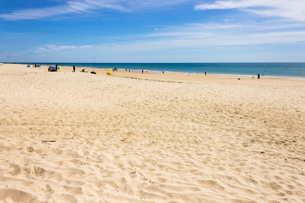 Szeroka piaszczysta plaża Ilha de Tavira nad oceanem, nieliczni plażowicze w oddali
