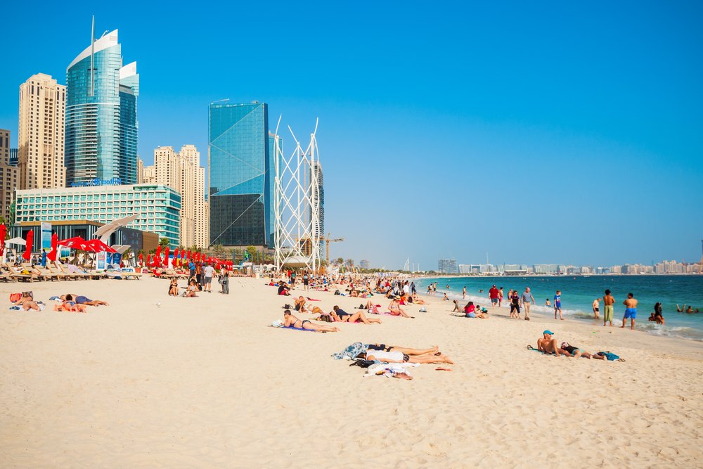 Publiczna plaża JBR z plażowiczami pod wieżowcami Dubai Marina