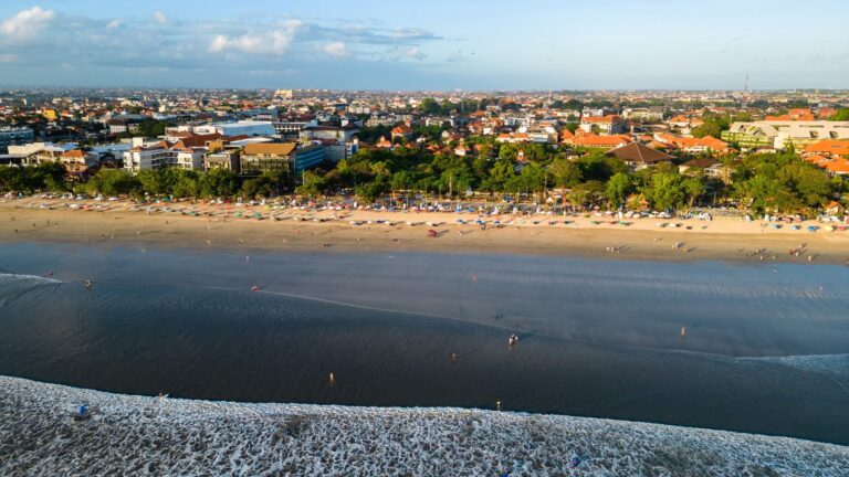 Szeroka plaża Kuta na Bali z miastem w tle, z lotu ptaka