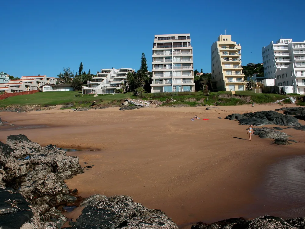 Piaszczysta zatoczka między skałami pod apartamentowcami w Ballito