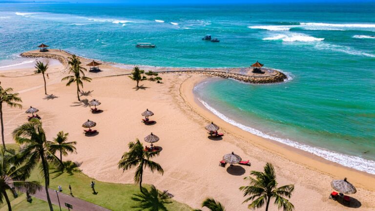 Plaża Nusa Dua z palmami i parasolami w strefie resortów, z lotu ptaka
