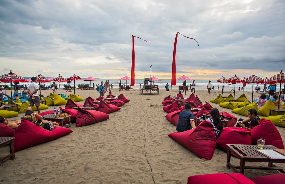 Czerwone pufy i parasole baru na plaży w Seminyaku pod wieczornym niebem