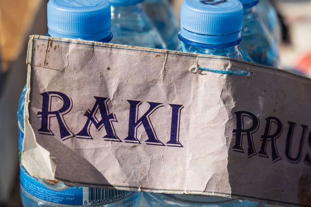 Raki w plastikowych butelkach po wodzie z odręcznym napisem RAKI RRUSH na straganie