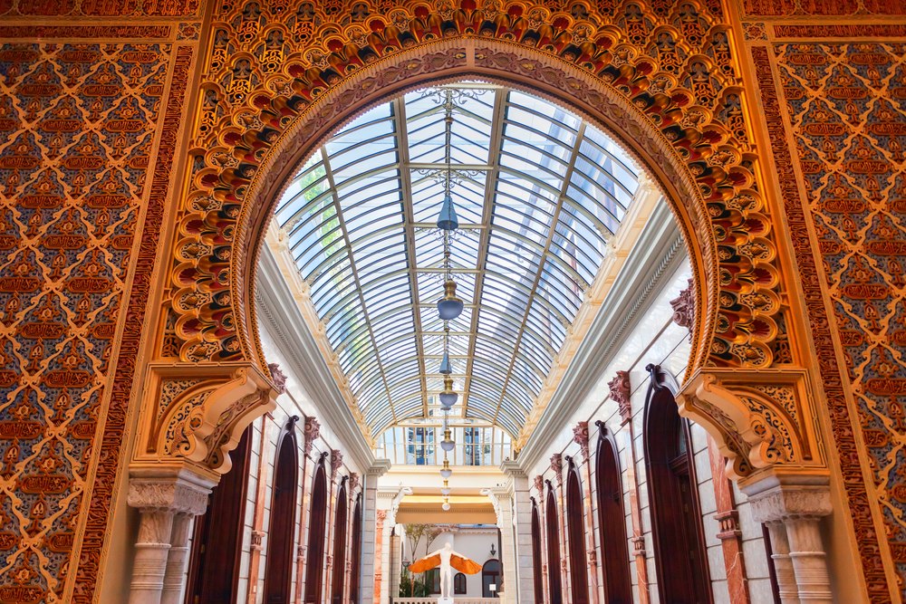 Patio arabskie Real Casino w Murcji: łuk podkowiasty z ornamentem i przeszklony dach nad krużgankiem