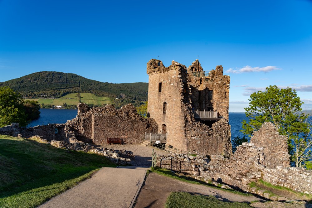 Wieża Grant Tower i mury zamku Urquhart nad jeziorem Loch Ness w słoneczny dzień