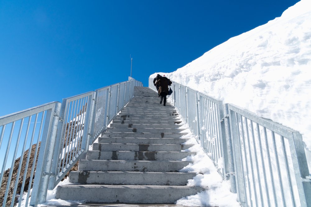 Schody w śniegu prowadzące na most Titlis Cliff Walk