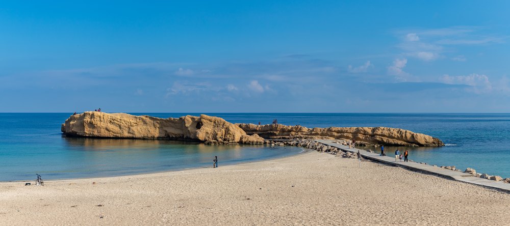 Skalista wysepka połączona groblą z piaszczystą plażą nad zatoką Karraiya w Monastyrze