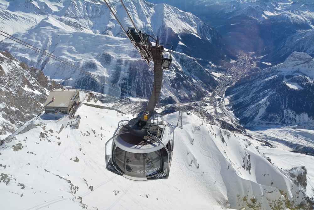 Kabina kolei Skyway Monte Bianco nad ośnieżonym grzbietem, w dole Courmayeur