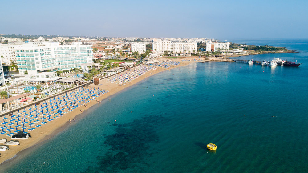 Sunrise Beach w Protaras z lotu ptaka, leżaki wzdłuż plaży i hotele przy brzegu