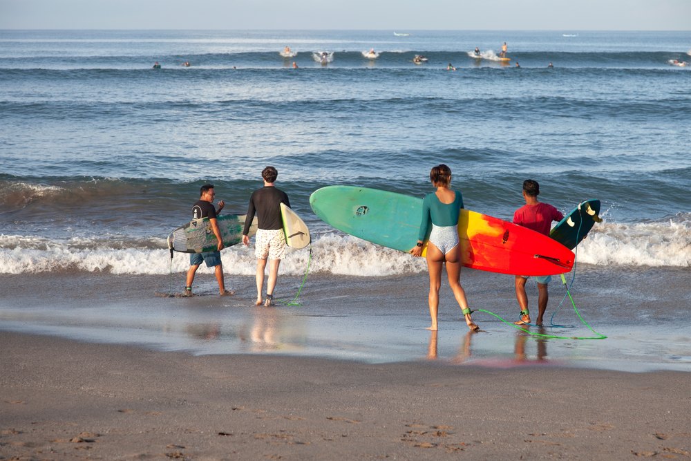 Surferzy z deskami wchodzą do wody na plaży Batu Bolong w Canggu