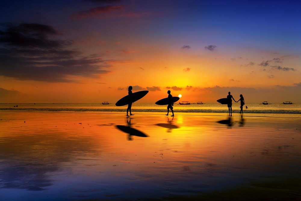 Surferzy z deskami na plaży Kuta na Bali o zachodzie słońca