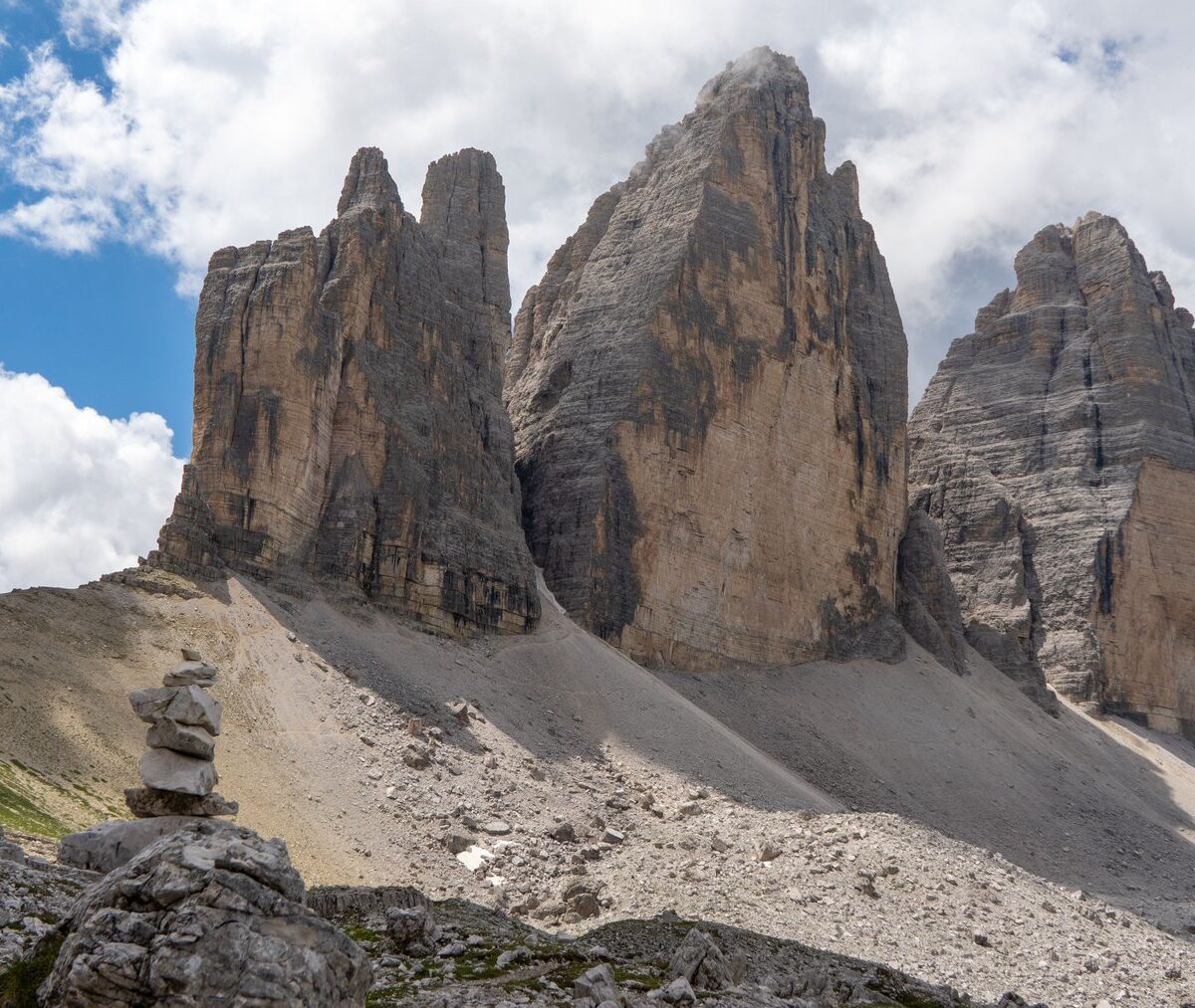 Trzy skalne wieże Tre Cime di Lavaredo nad piargiem, przy szlaku kamienny kopczyk