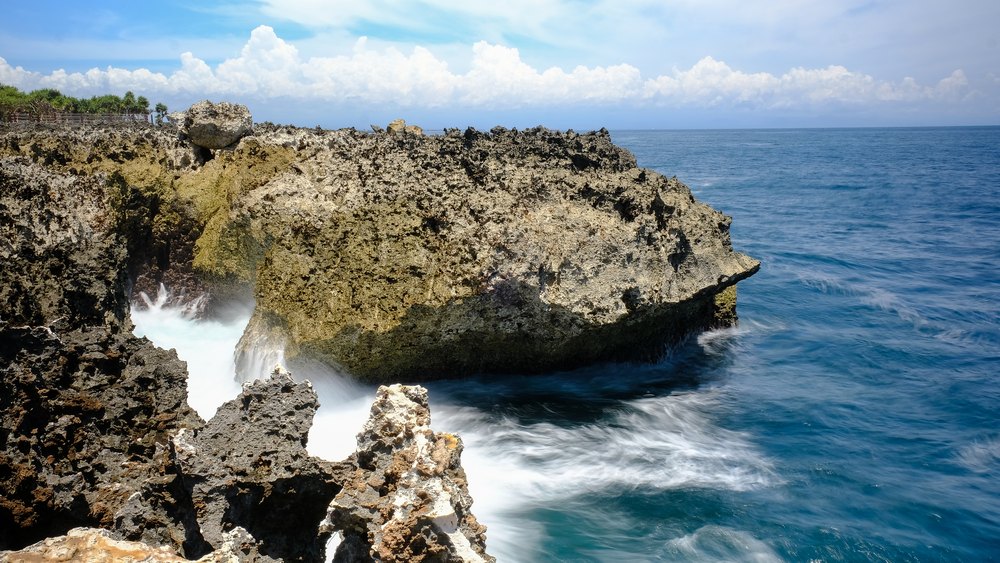 Fala wpływająca w szczeliny wapiennej skały Water Blow w Nusa Dua
