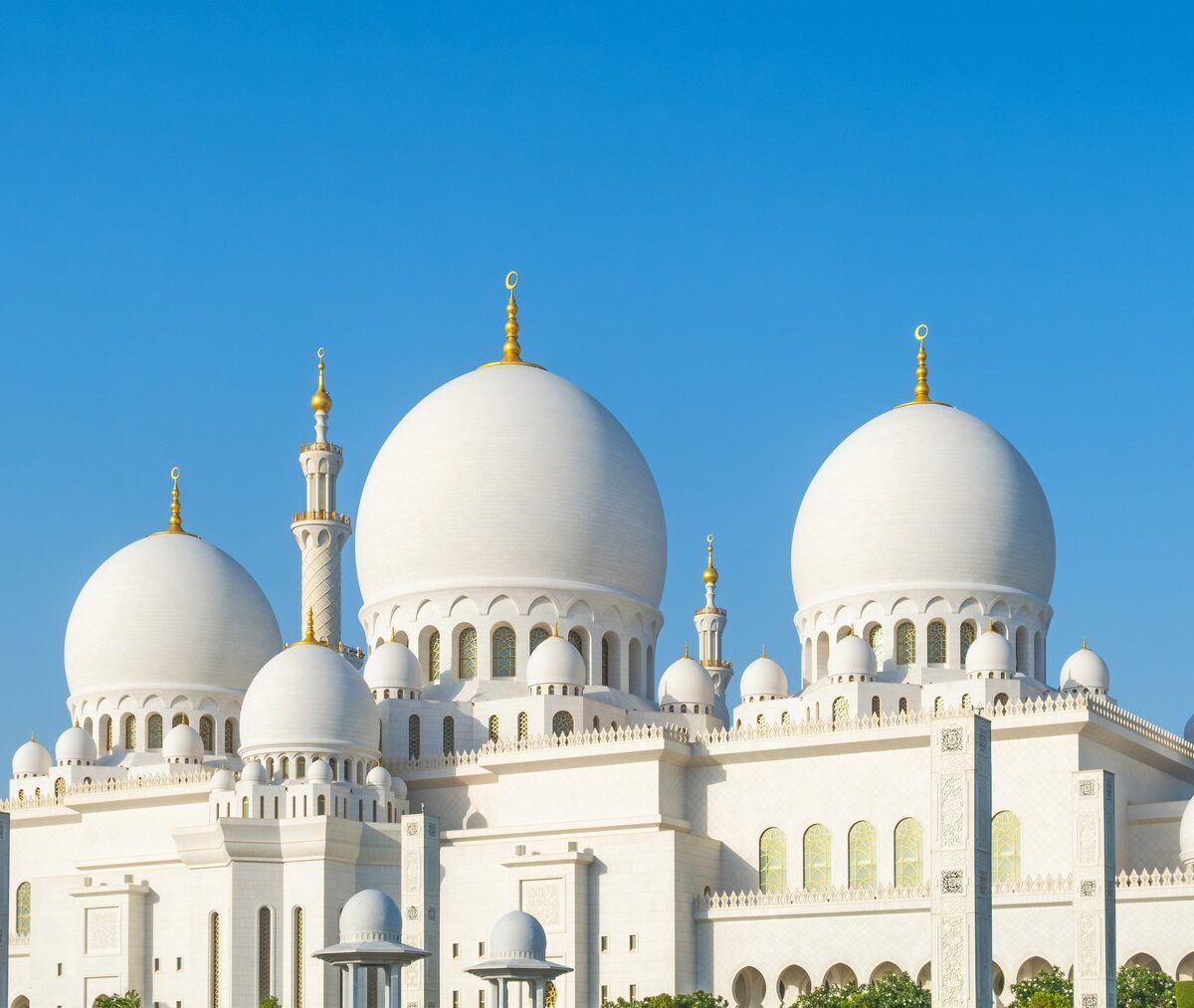 Białe kopuły i minarety Wielkiego Meczetu Szejka Zajida w Abu Zabi pod błękitnym niebem