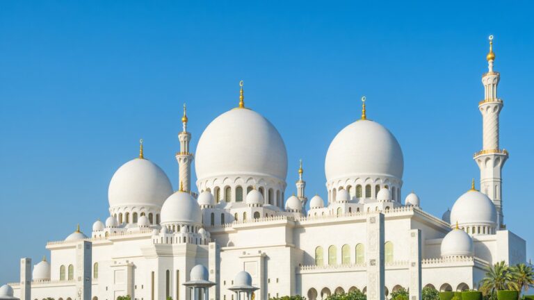 Białe kopuły i minarety Wielkiego Meczetu Szejka Zajida w Abu Zabi pod błękitnym niebem