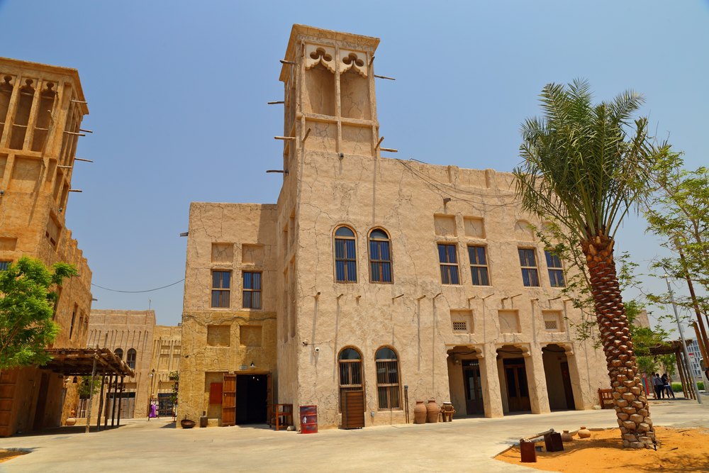 Kamienny dom z wieżą wiatrową i palmą w historycznej dzielnicy Al Fahidi w Dubaju