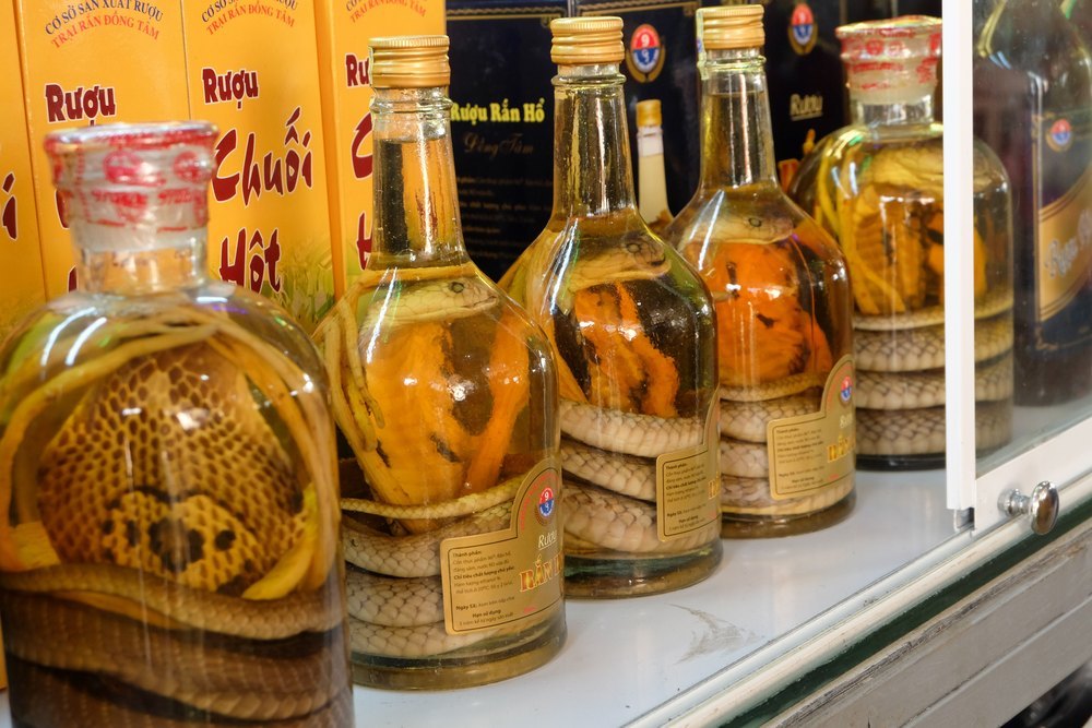 Butelki wódki ryżowej z zatopionymi wężami, w tym kobrą, na półce sklepu