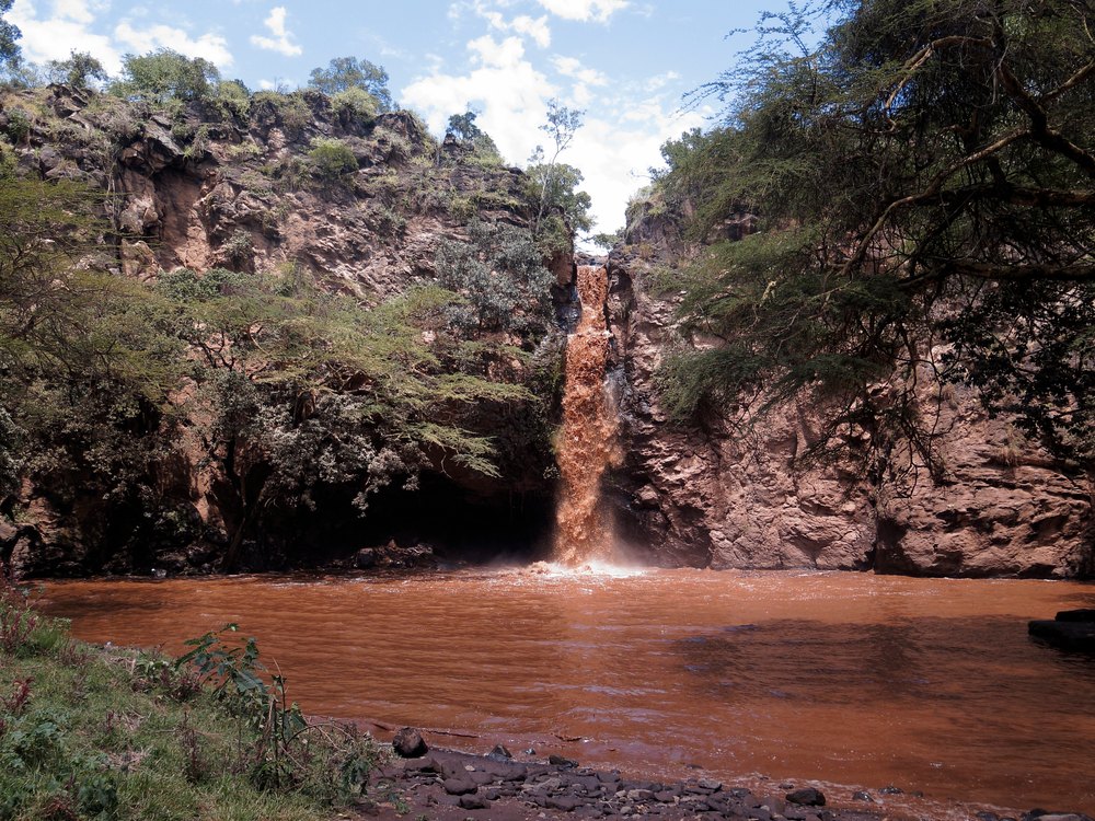 Wodospad Makalia spadający ze skał do brązowego stawu w Lake Nakuru