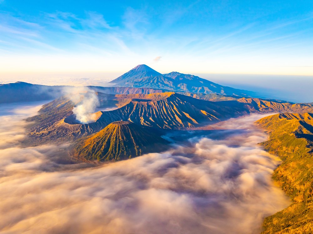 Dymiący krater Bromo nad morzem mgieł o wschodzie słońca, w tle Semeru, z lotu ptaka