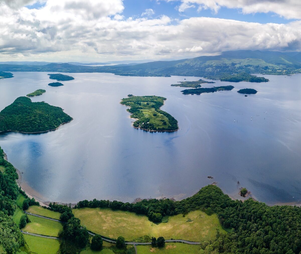 Zalesione wyspy na jeziorze Loch Lomond z lotu ptaka, w dali góry parku narodowego