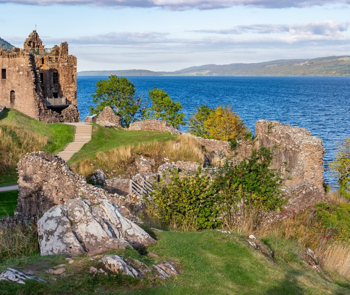 Ruiny zamku Urquhart na brzegu jeziora Loch Ness, w dali wzgórza nad wodą