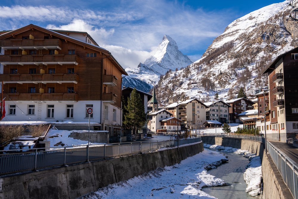 Drewniane domy i potok w Zermatt zimą, w tle Matterhorn