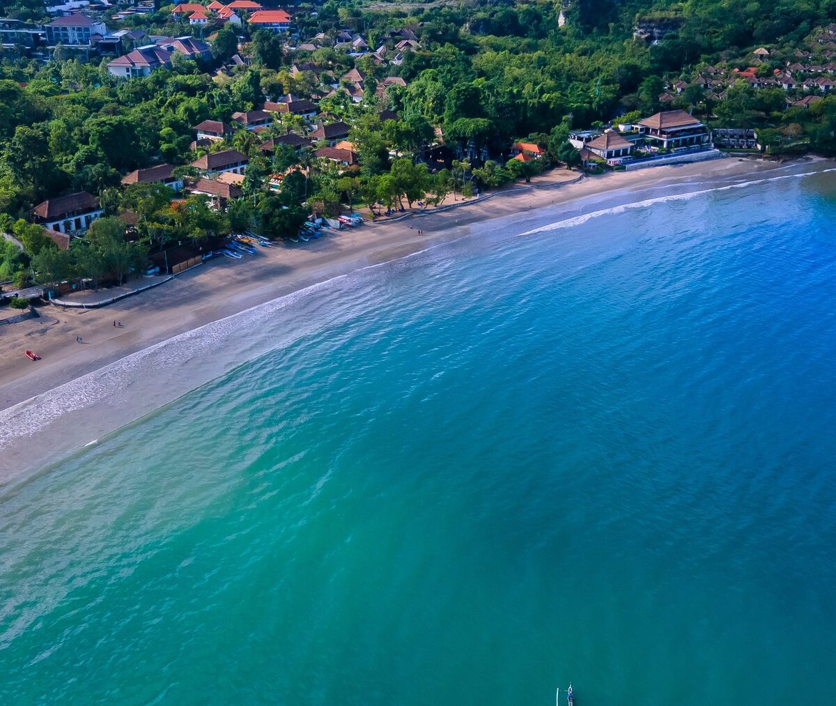Łuk zatoki Jimbaran z jasną plażą i spokojną wodą, z lotu ptaka