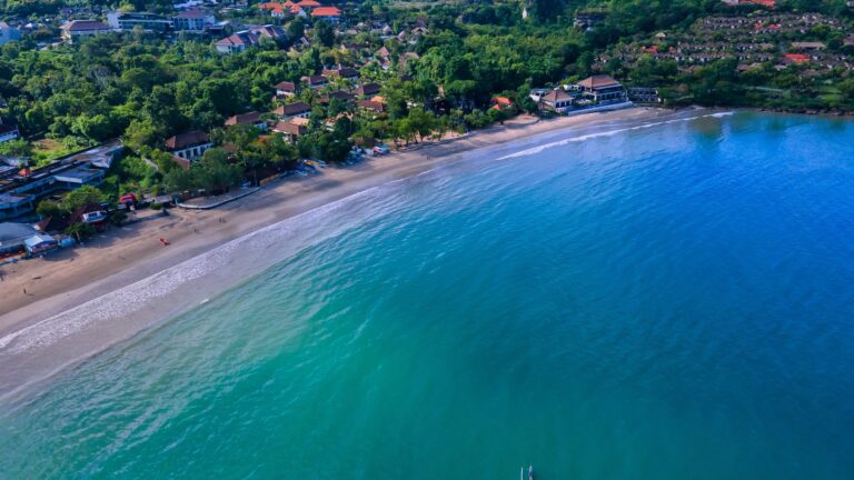 Łuk zatoki Jimbaran z jasną plażą i spokojną wodą, z lotu ptaka