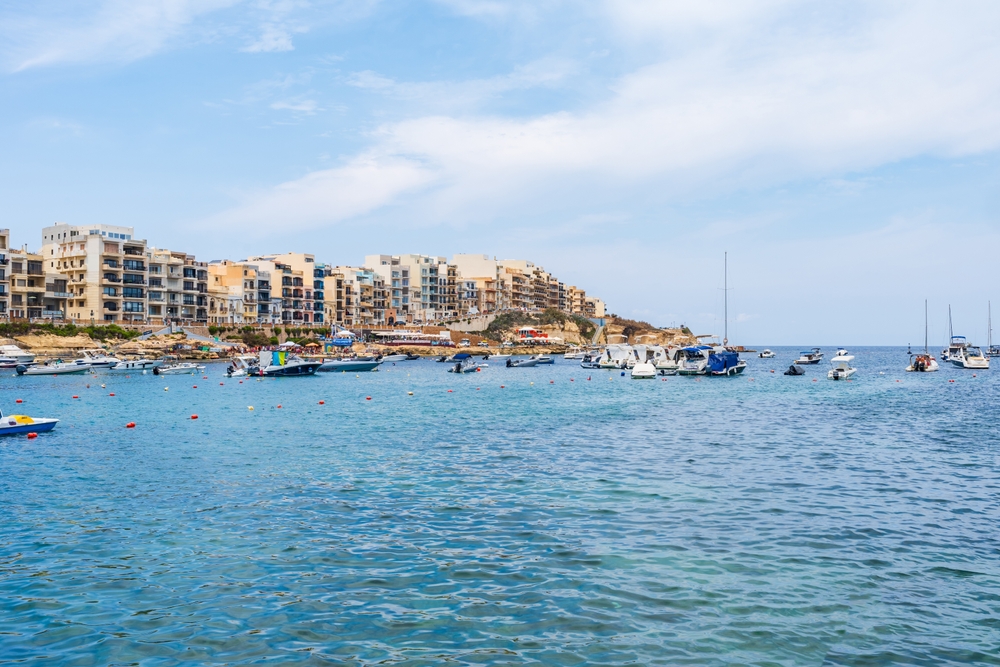 Zatoka Marsalforn na Gozo z łodziami na wodzie i apartamentowcami nad brzegiem
