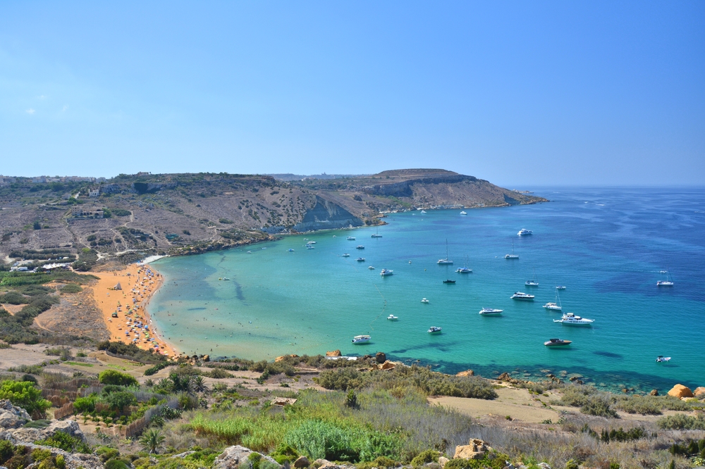 Zatoka Ramla na Gozo z plażą z czerwonawego piasku i jachtami na kotwicy, widok ze wzgórza