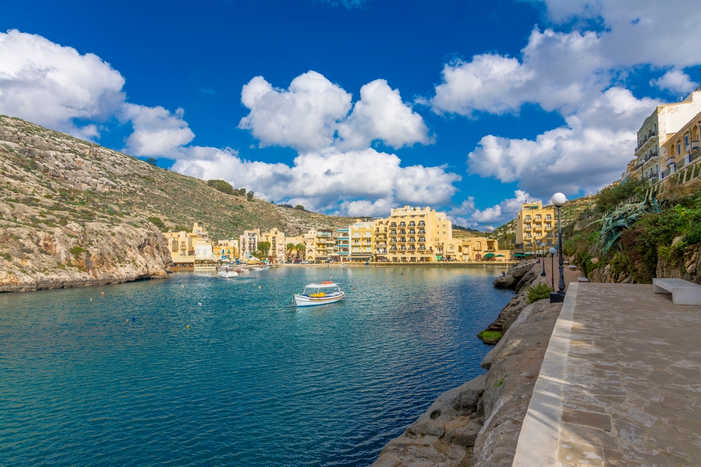 Wąska zatoka Xlendi na Gozo z łodzią na wodzie, promenadą i hotelami u wylotu doliny