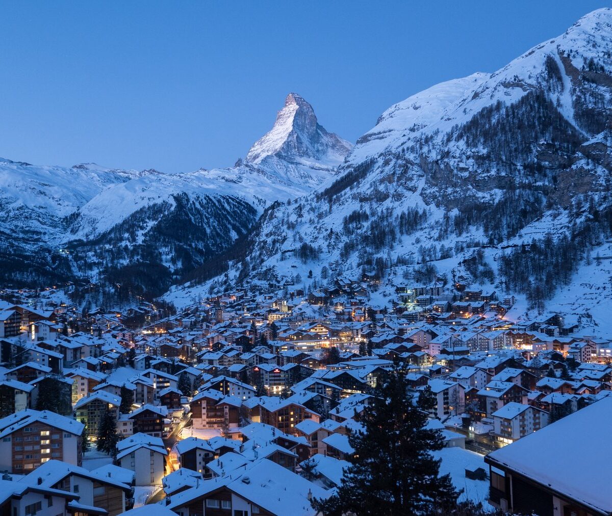 Zaśnieżona wieś Zermatt o zmierzchu, nad doliną szczyt Matterhornu